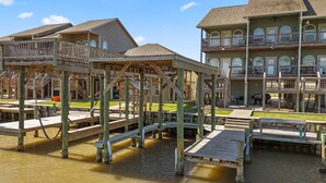 Una proprietà fronte mare con diverse terrazze in legno e un edificio più grande con balconi.