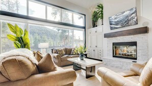 A modern living room with a large window, a fireplace, and a view of a mountainous landscape. - Keystone 5BD 5.5BT Luxury Remodel 2025 & Pets (Keystone)