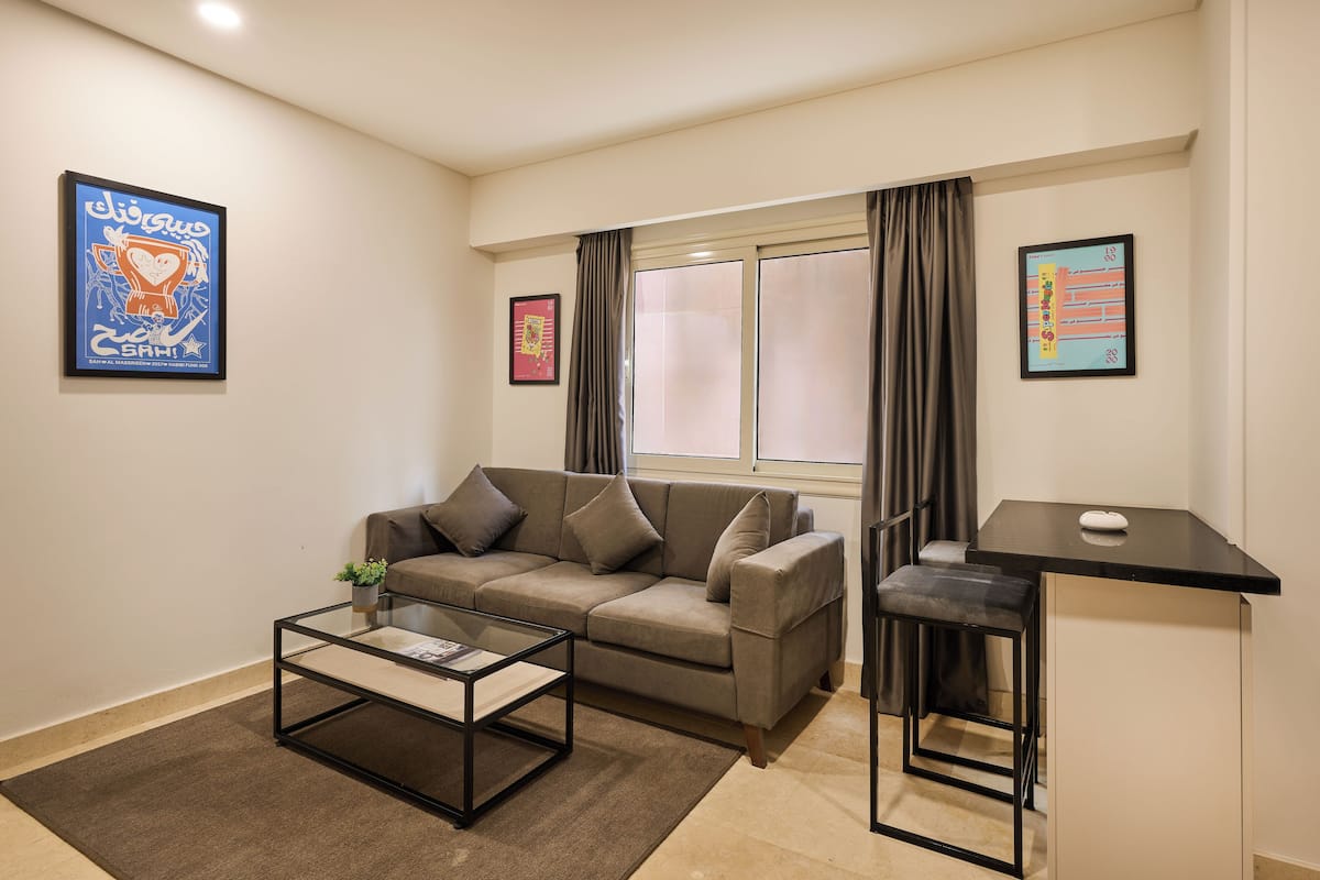 A modern living room with a sofa, a coffee table, a small side table, and a window with curtains.