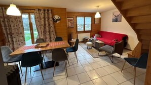 A cozy room with a wooden dining table, chairs, a red sofa, and a staircase. - Cosy chalet 2-8pers/linen provided (Gérardmer)