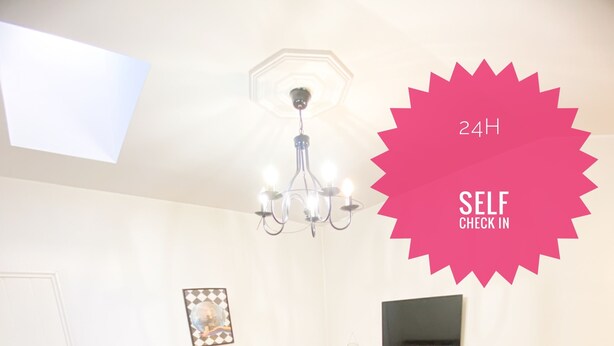 A furnished room with a sofa, a chair, a desk, a TV, and a chandelier. - Vintage Loft in the center (Cluj-Napoca)