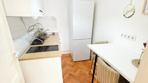 A compact kitchen with a white refrigerator, a wooden countertop, and a herringbone-patterned wooden floor. - Vintage Loft in the center (Cluj-Napoca)