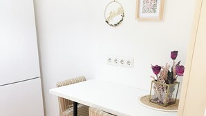 A small kitchen with a white countertop, two striped chairs, a white refrigerator, and a framed picture on the wall. - Vintage Loft in the center (Cluj-Napoca)