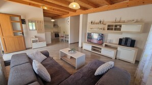 A modern living room with a sofa set, a coffee table, and a TV. There is a kitchen area with cabinets and a dining table. - Villa Edo beautiful built villa with private pool in a small village in Istria (ZMINJ)