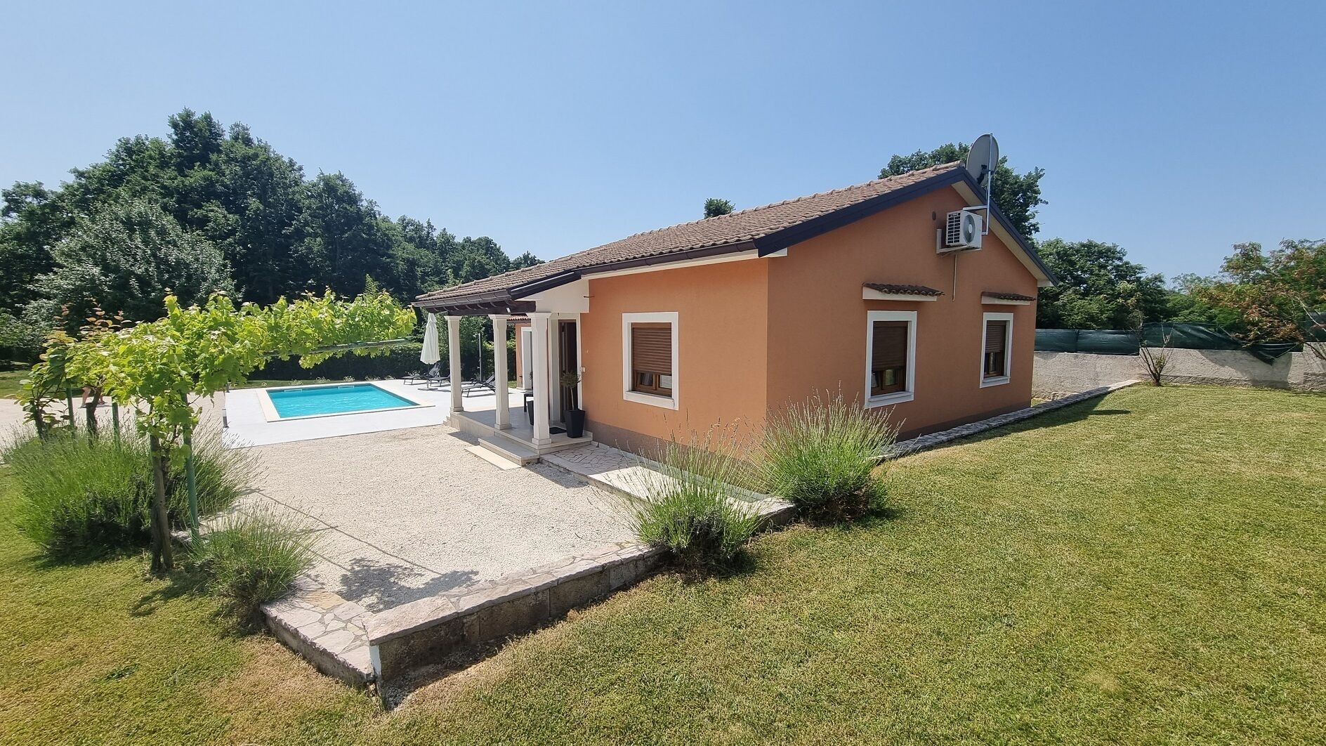Une maison de plain-pied avec une piscine, un patio couvert et une pelouse bien entretenue.