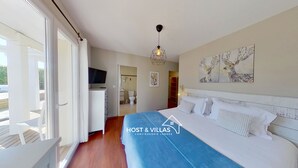 A bedroom with a bed, a TV, a bathroom, and a balcony.