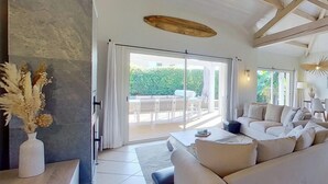 A modern living room with a sofa, a coffee table, and a view of the outdoors through a sliding glass door.