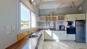 A modern kitchen with a sink, stove, and microwave. There are cabinets and a window providing natural light.