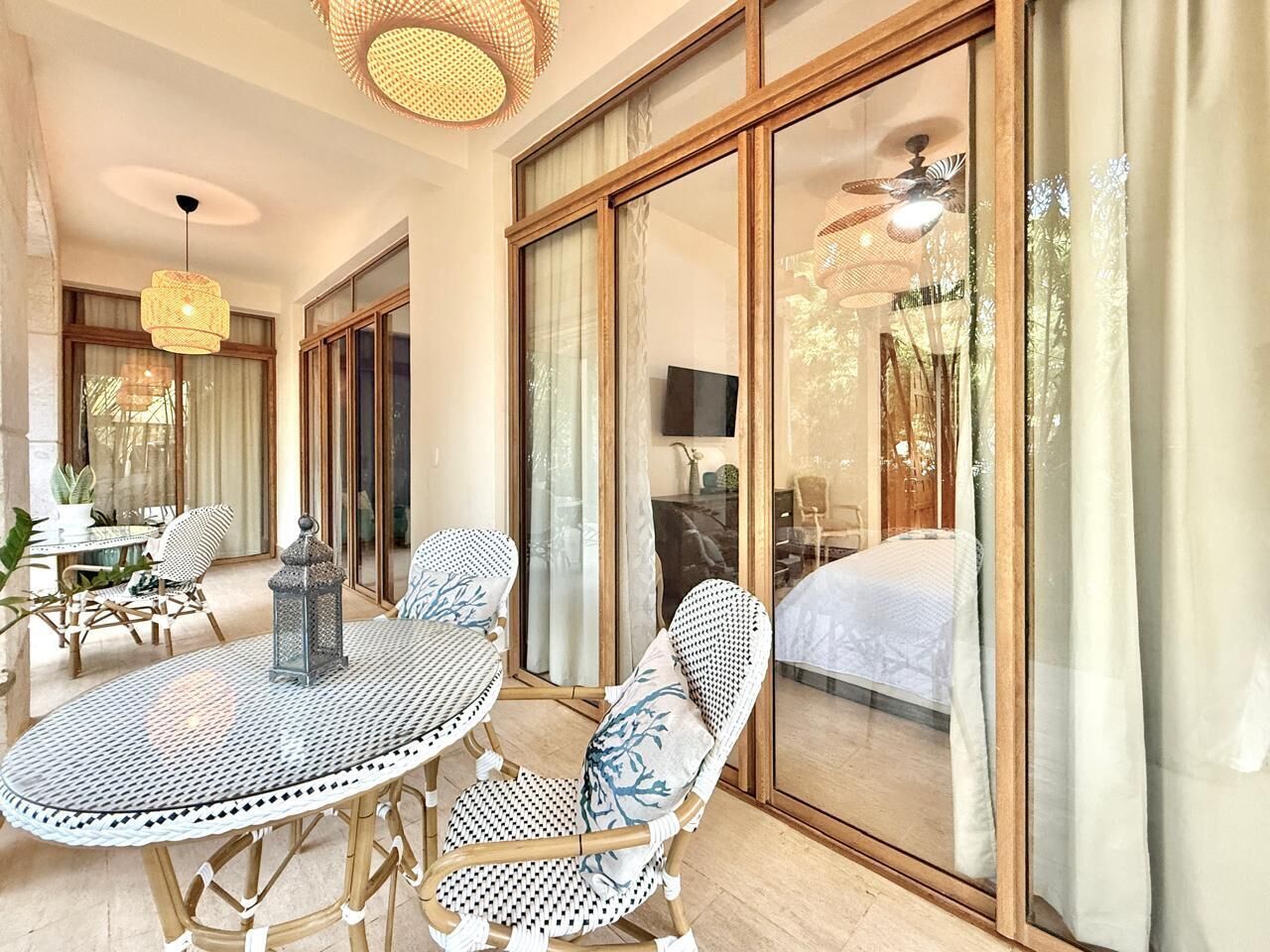 A spacious room with a large sliding glass door leading to a balcony, a round dining table with chairs, and a ceiling fan.