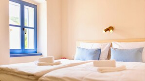 Een hotelkamer met een bed, een raam en een wandlamp.