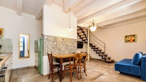 Een keuken met een eettafel en stoelen, een groene koelkast, en een trap naar een ander niveau.