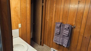 Un baño con paneles de madera, un lavabo blanco y un perchero con toallas.