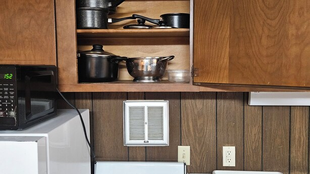 Una cocina compacta con estufa blanca, microondas y armarios de madera.