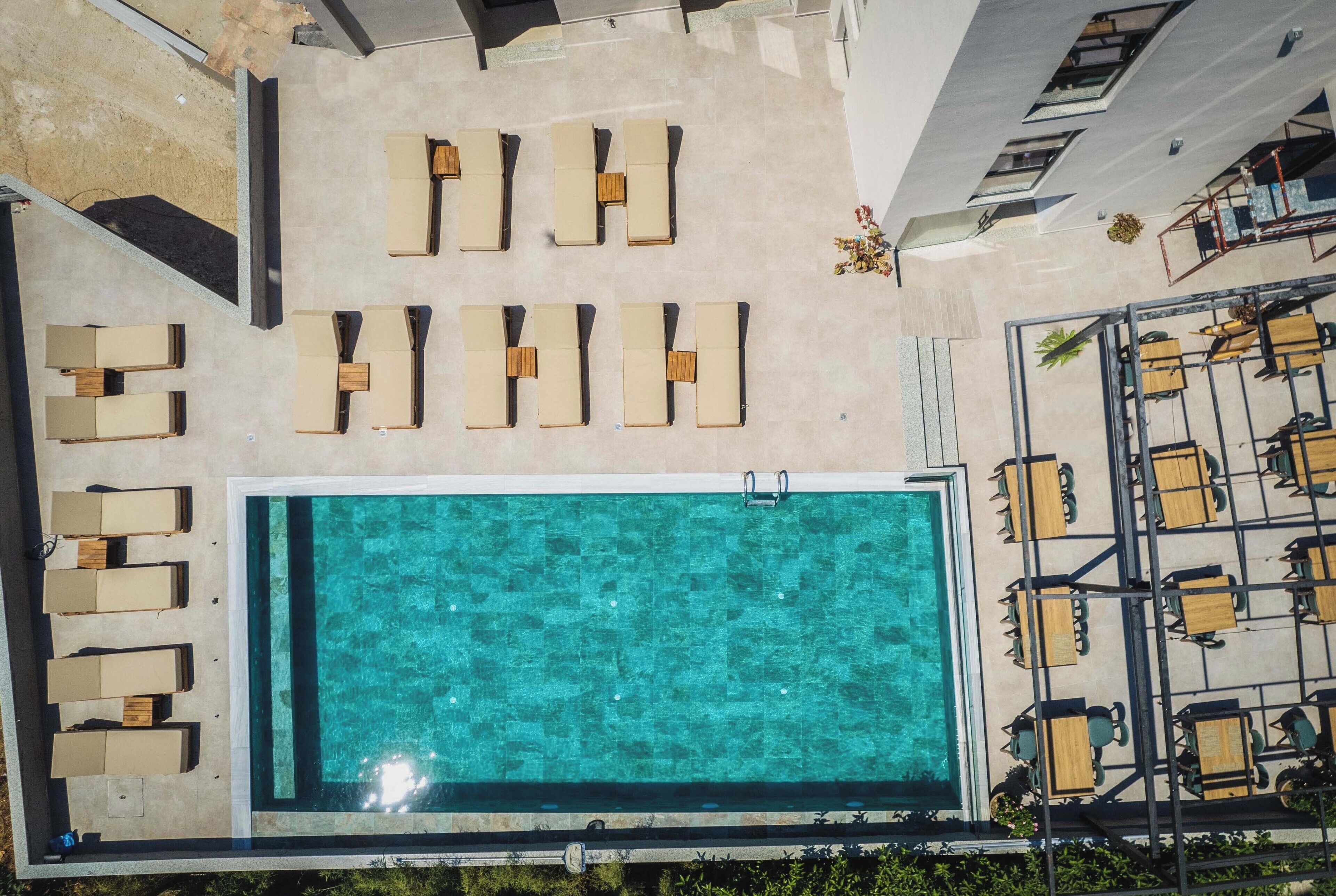 An aerial view of a rooftop pool area with lounge chairs and a swimming pool.