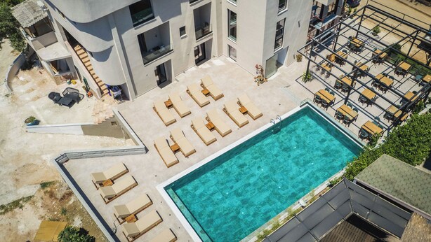 A modern building with a rooftop pool, multiple lounge areas, and outdoor seating. - Hotel ENAD (Ksamil)