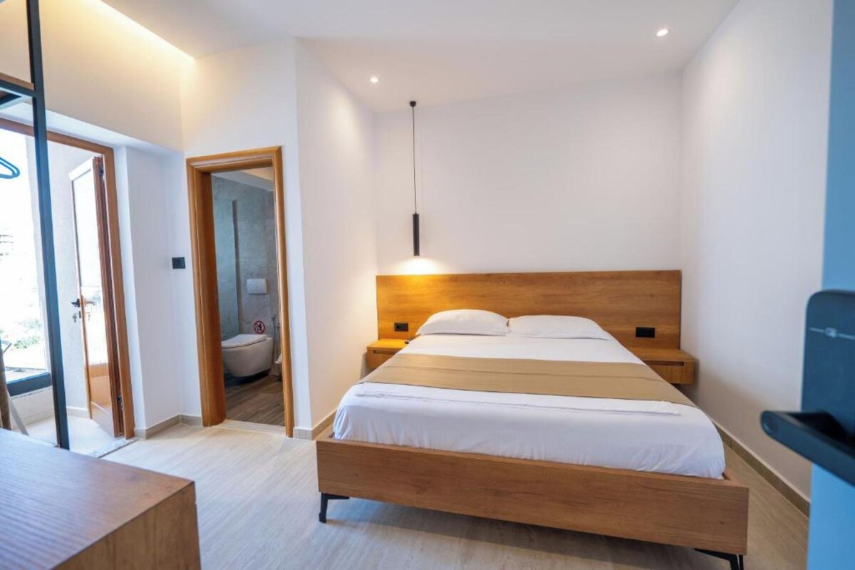 A modern bedroom with a wooden bed, bedside tables, and a hanging light fixture.
