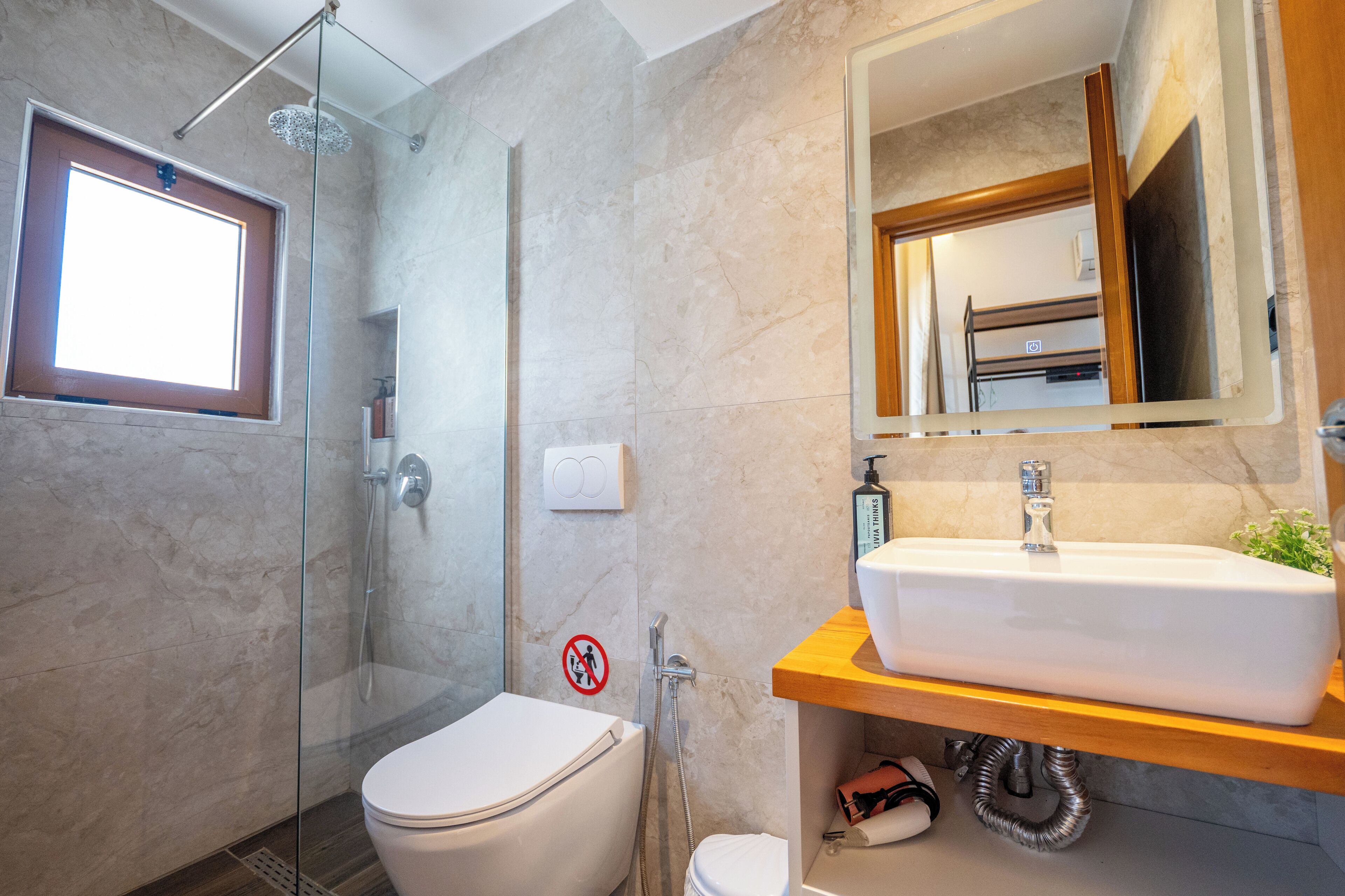 Ein modernes Badezimmer mit einer Duschkabine aus Glas, einer weißen Toilette und einem Holzwaschtisch.