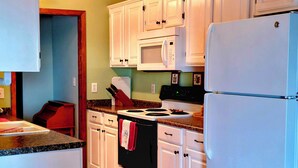 A kitchen with white cabinets, a microwave, a stove, and a refrigerator. - Home, Hooks & Heart: Anglers Paradise Family-Friendly Bay House Marina 2 Blocks (Corpus Christi)