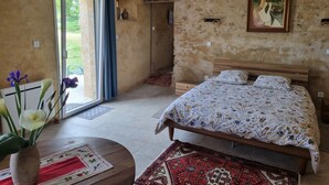 A bedroom with a bed, a painting, a vase with flowers, and a view of the outdoors. - Unique Vacation Rental: Le Boupère la Forestrie, Puy du Fou (Le Boupère)