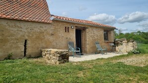 A rustic building with a tiled roof, a stone wall, and two outdoor chairs. - Unique Vacation Rental: Le Boupère la Forestrie, Puy du Fou (Le Boupère)