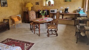 A dining area with a round table, chairs, a lamp, and a window with a view. - Unique Vacation Rental: Le Boupère la Forestrie, Puy du Fou (Le Boupère)