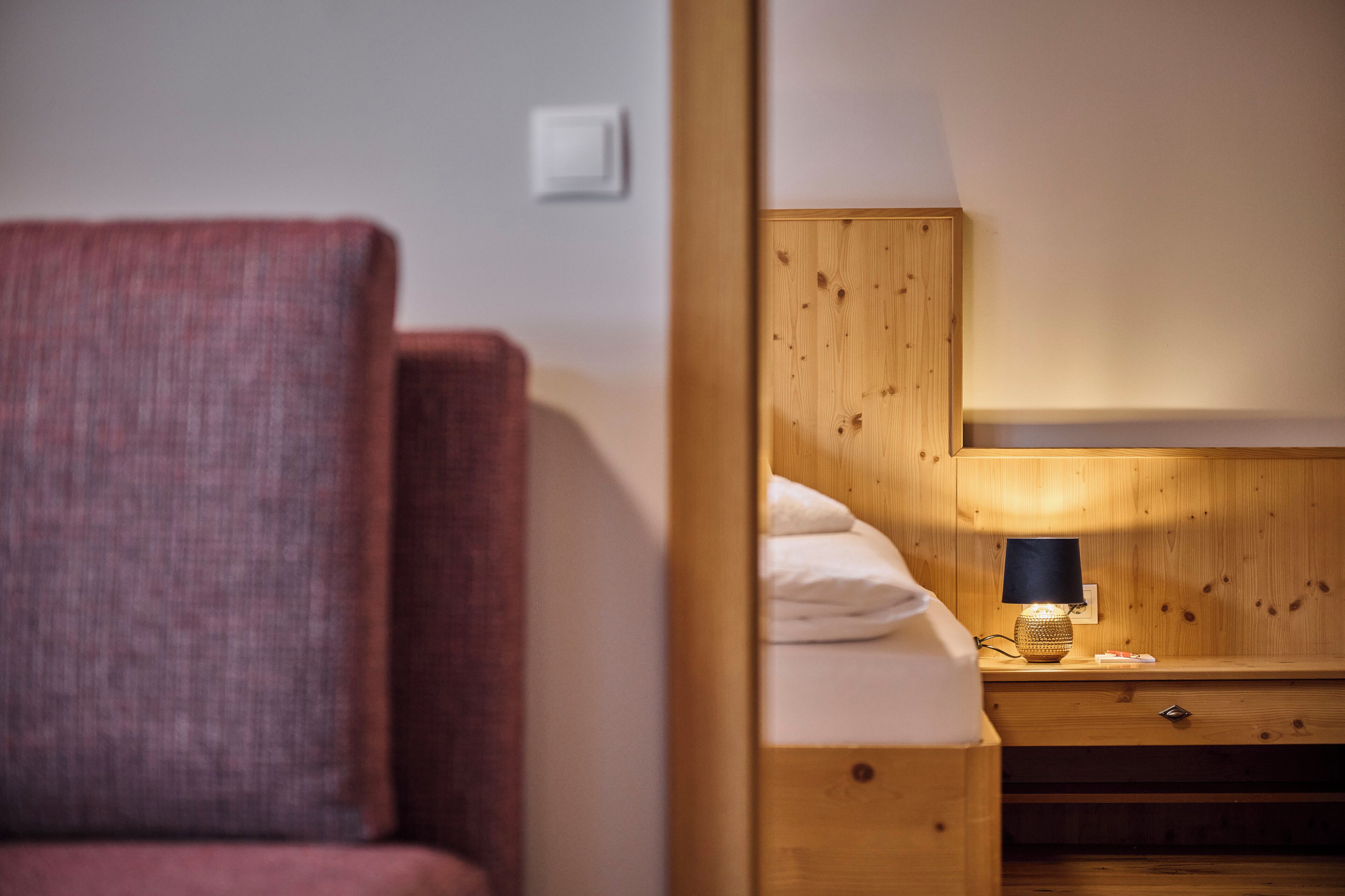 A wooden bunk bed with a nightstand and a lamp.