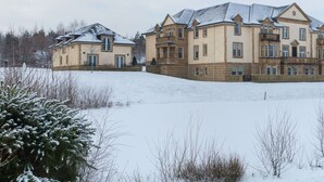 A large, multi-story building with a symmetrical facade, multiple balconies, and a snow-covered landscape.
