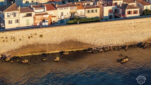 Eine Küstenstadt mit terrakottafarbenen Dächern, einer Steinmauer und freiem Blick auf das Meer.