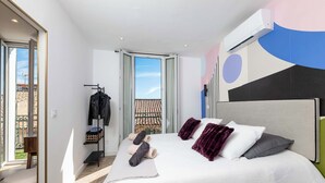 Ein modernes Schlafzimmer mit einem großen Bett, einem Kleiderschrank und Blick auf den Balkon.