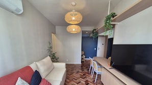 A modern living room with a sofa, TV, and herringbone-patterned flooring.
