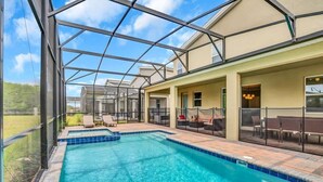 Une piscine extérieure couverte, dotée d’une structure en verre, de chaises longues et d’un espace patio aménagé avec du mobilier d’extérieur.