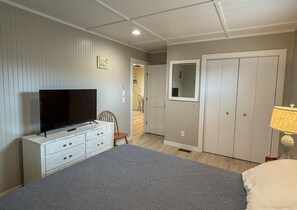 A bedroom with a bed, a dresser, a television, a wardrobe, and a mirror. - Sea-Esta Downstairs: On the Canal with Boat Dock (Ocracoke)