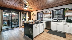 Una cocina moderna con una isla central, armarios blancos y techo de madera.
