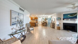 A spacious living room with a fireplace, dining area, and kitchen in the background. - Gorgeous Panoramic Views!  Stairs DIRECTLY to the beach!  PELICANS POINTE 5C (Indian Shores)