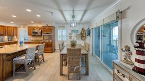 A spacious kitchen with wooden cabinets, a large island with bar stools, and a dining area with a table and chairs. - Gorgeous Panoramic Views!  Stairs DIRECTLY to the beach!  PELICANS POINTE 5C (Indian Shores)