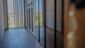 Un couloir donnant sur un espace extérieur, avec un aménagement moderne comprenant des stores verticaux et un sol carrelé.