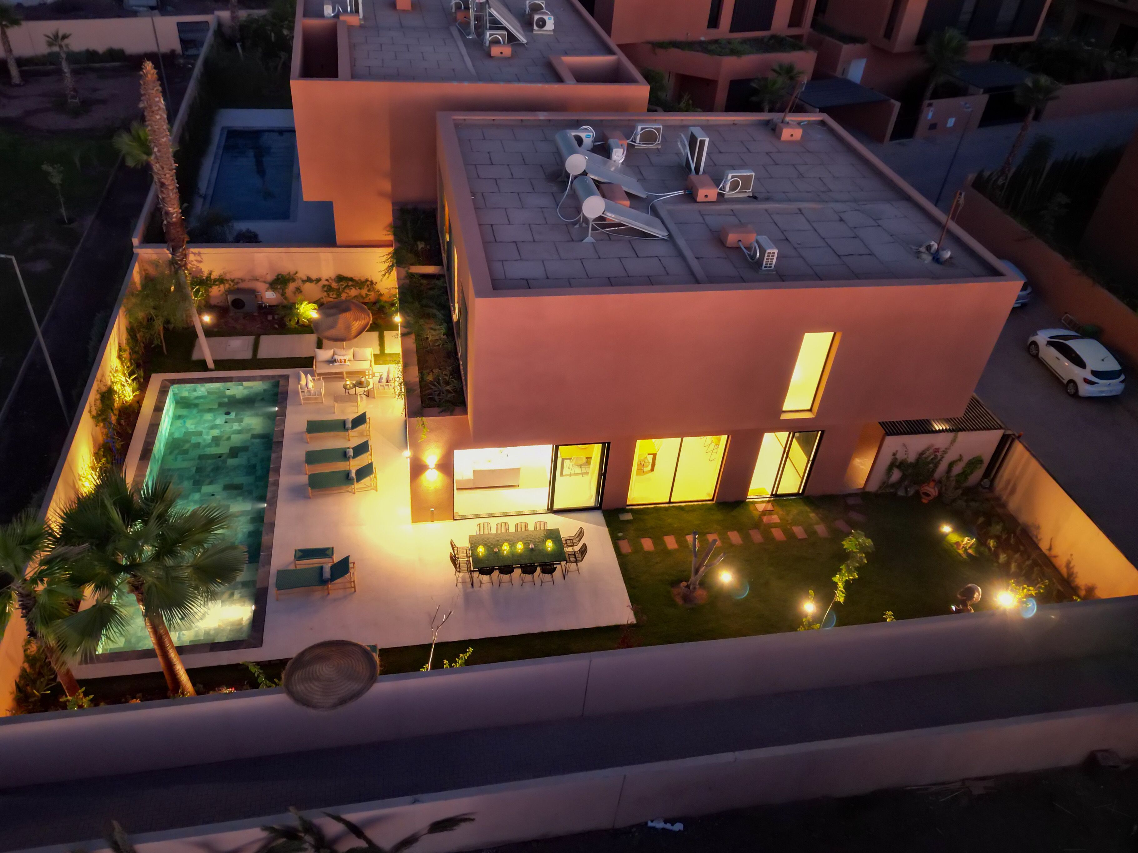 A modern house with a swimming pool, outdoor seating, and a well-lit patio area.