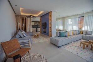 A modern living room with a sofa, chairs, a dining area, and a kitchen in the background. - Villa Marleanis (Marrakech)