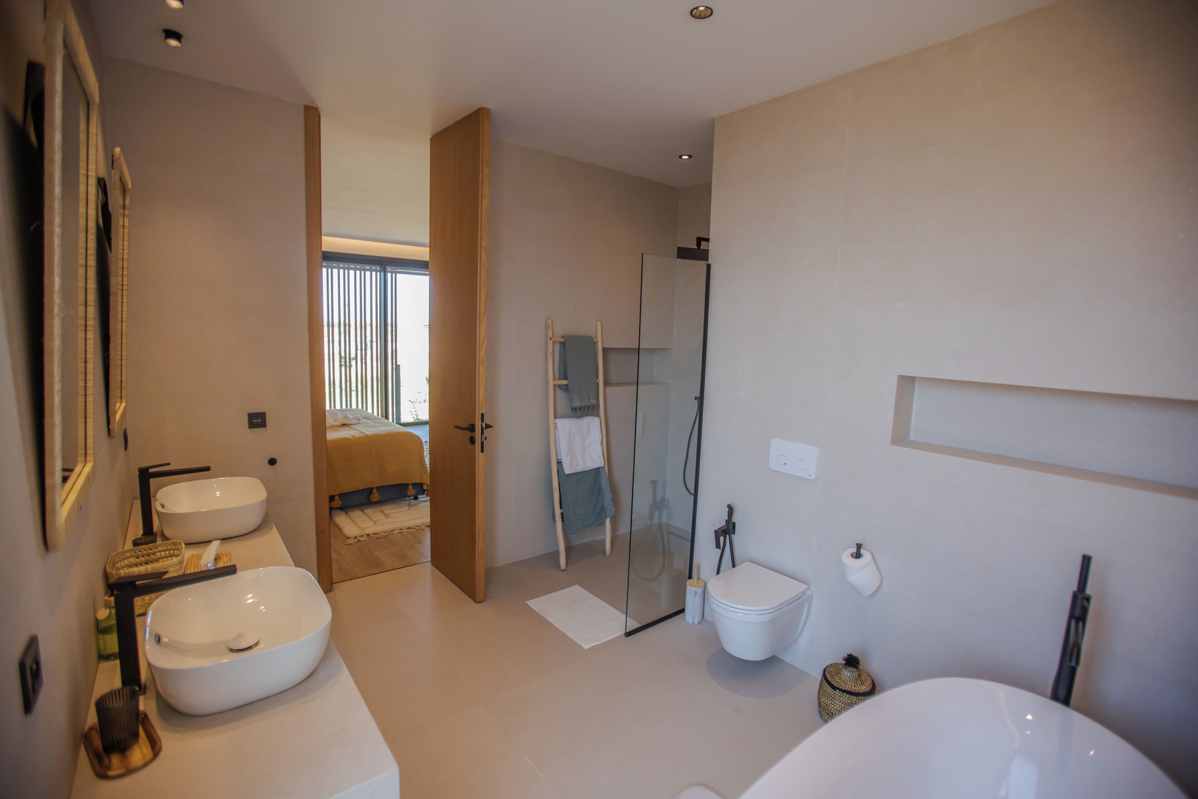 A modern bathroom with two sinks, a toilet, and a shower area.