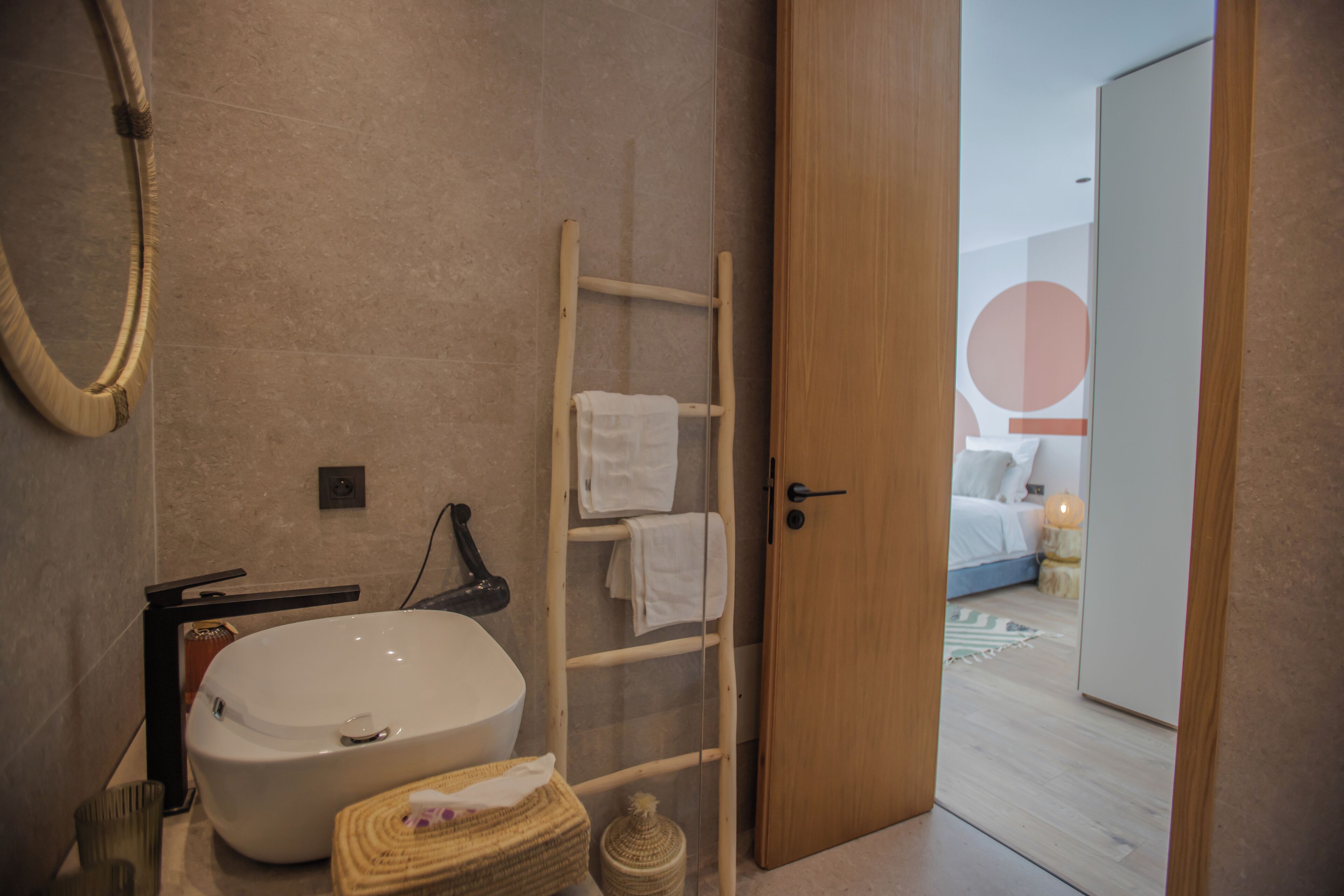 Une salle de bain avec un grand lavabo blanc, un porte-serviettes en bois et un panier à serviettes.
