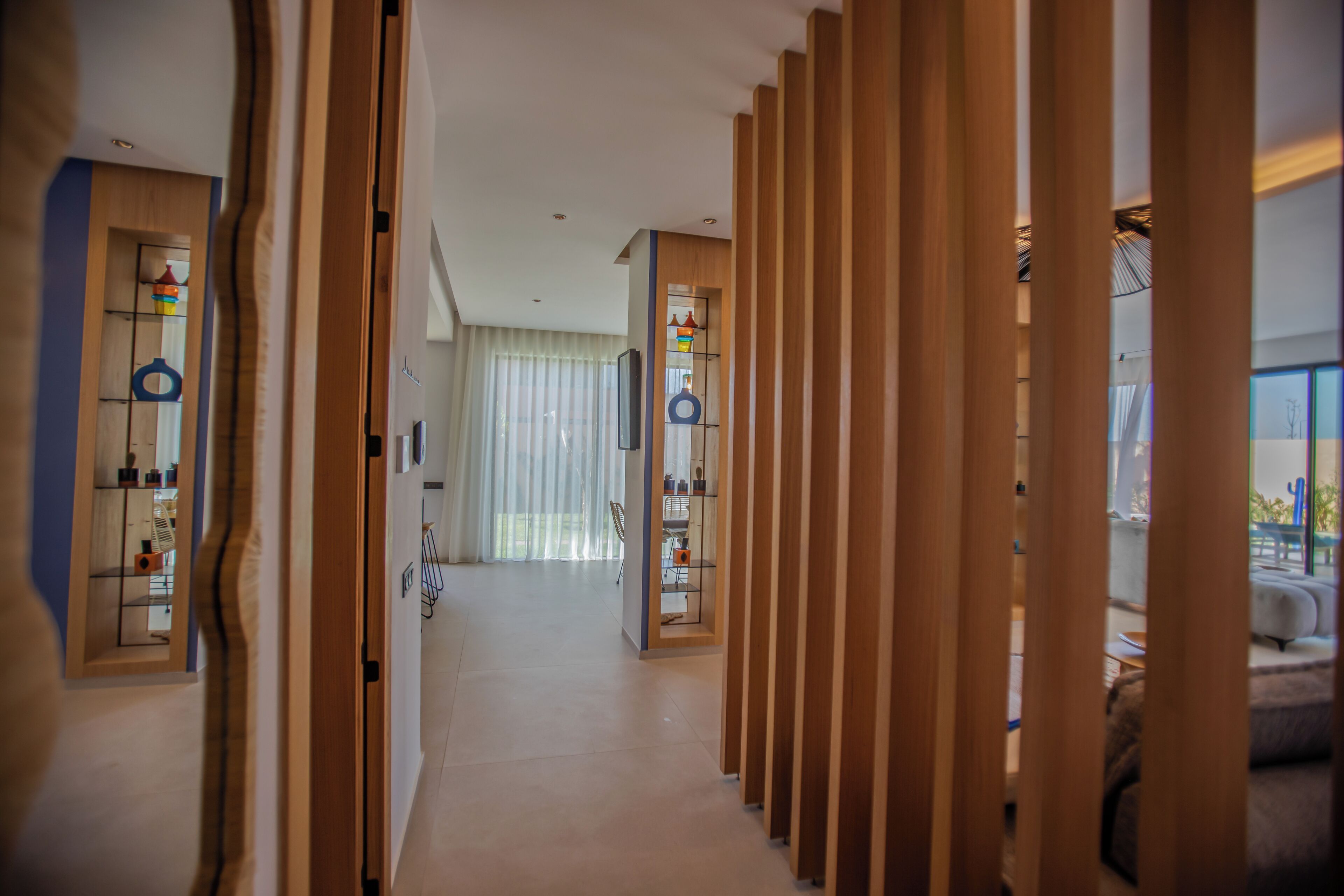 Un pasillo con paneles de madera, un ventilador de techo y vistas a una sala de estar con un sofá y una mesa.