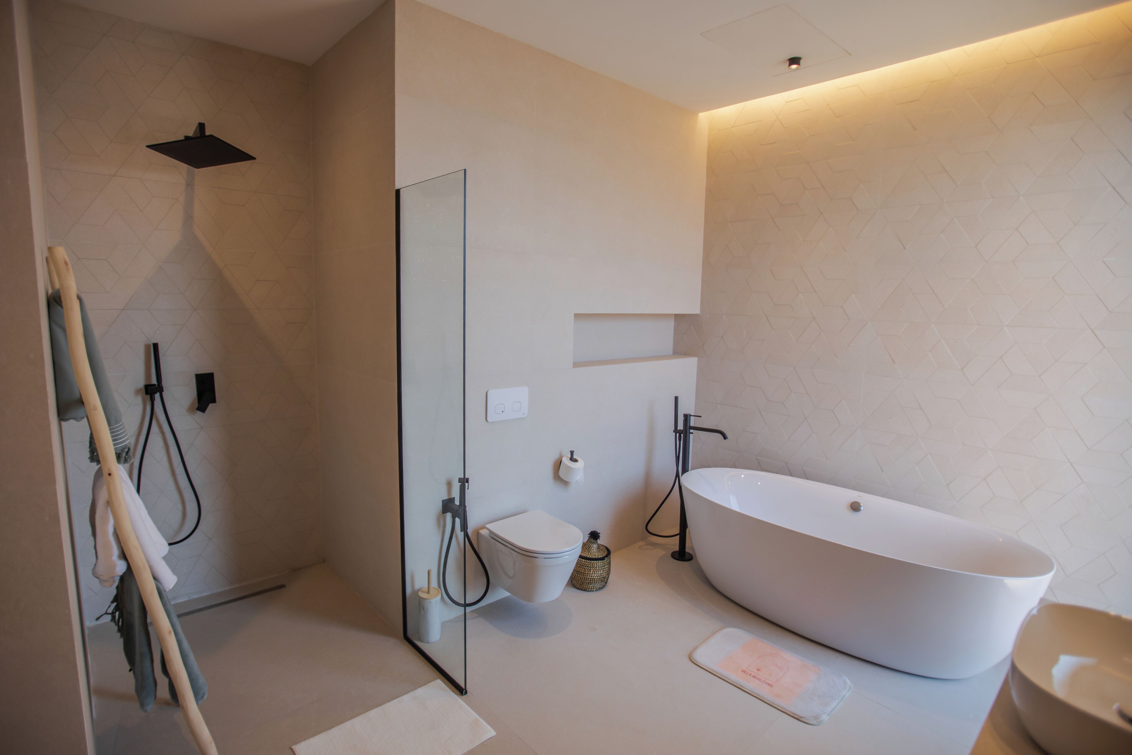 Een moderne badkamer met een vrijstaand bad, toilet en een douchehoek.