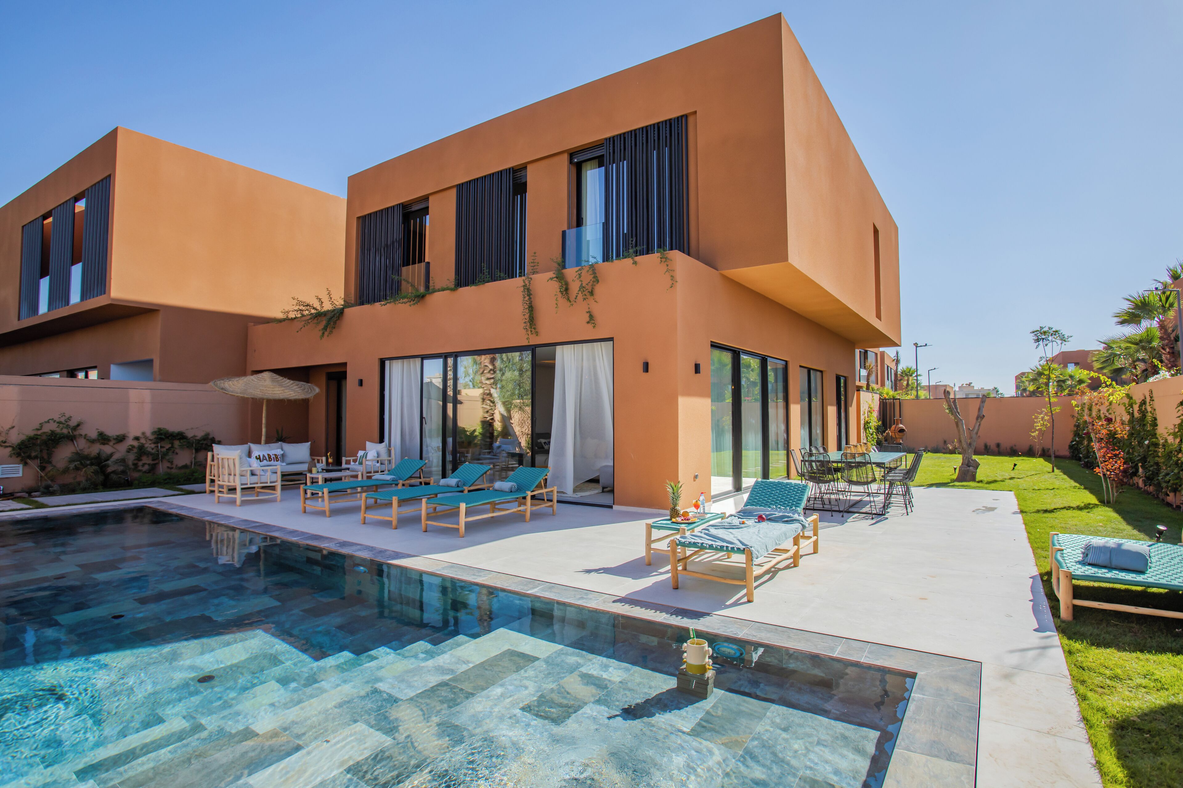 A modern house with a swimming pool, outdoor seating, and a well-maintained garden.