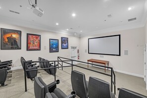 A home theater room with a large screen, multiple seating areas, and movie posters on the walls. - Spacious 3-bedroom condo Just Mins from Disney! (Kissimmee)