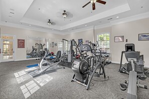A gym with various exercise equipment, large windows, and a ceiling fan. - Spacious 3-bedroom condo Just Mins from Disney! (Kissimmee)