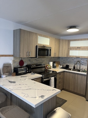 Una cocina moderna con armarios de madera, un microondas integrado, una estufa y una isla grande con encimera de mármol.