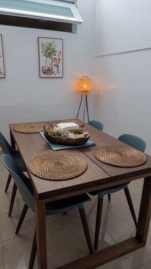 Una mesa de comedor con individuales tejidos, un centro de mesa y sillas azules.
