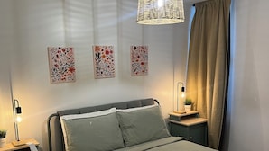 Ein ordentlich eingerichtetes Schlafzimmer mit Bett, Nachttischen, einer Pendelleuchte und Wandbildern.