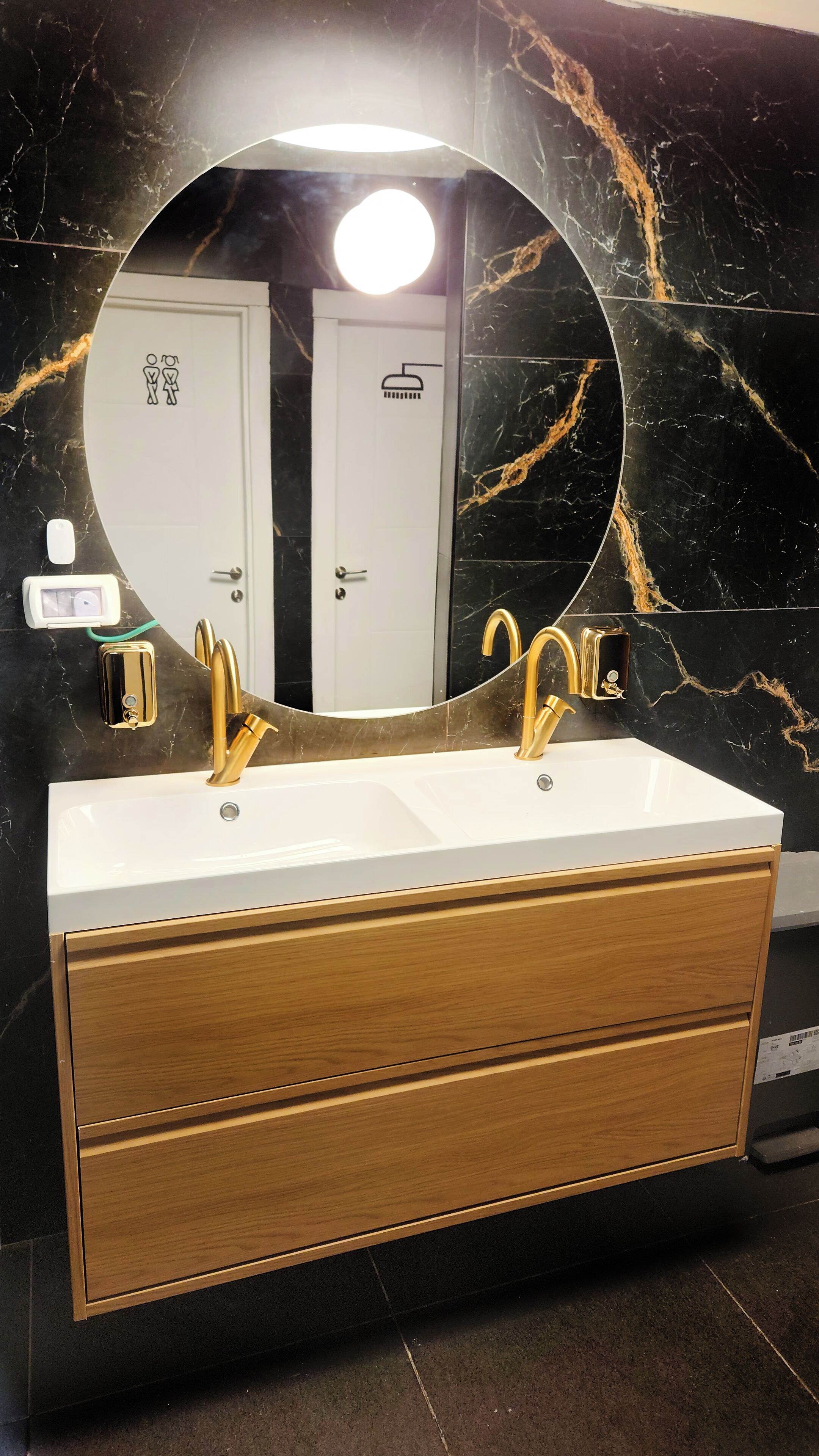 A bathroom with a white sink, gold faucets, and a wooden vanity.