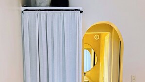 A room with a white curtain, a wooden floor, and a doorway leading to another room with a mirror and a shelf. - Ipanema Premium Design · Renovated · Steps to Beach & Subway (Rio de Janeiro)